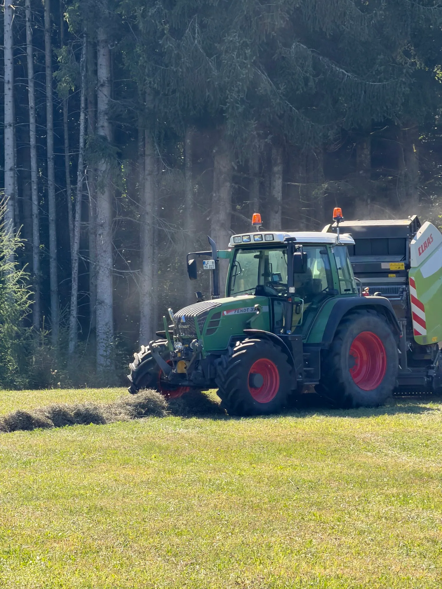 Grüner Fendt-Schlepper mit Claas Presse im Einsatz am Feldrand